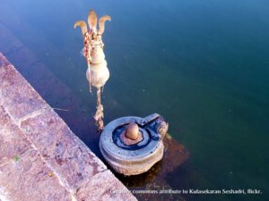 shiva linga on river ghat with trident