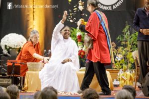 Amma showers a guest with flowers as She gets garlanded