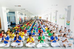 amrita yoga large hall of children in namaste